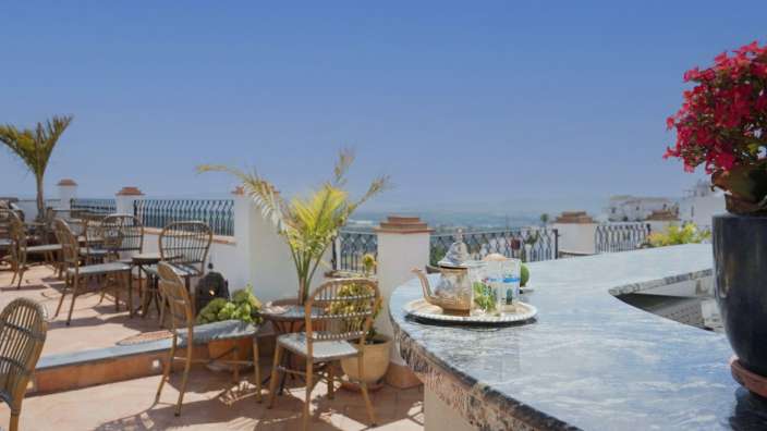 Eine Terrasse mit Tisch und Stühlen und einer Teekanne auf einem Tisch