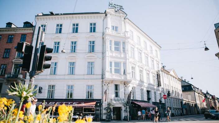 Eine Gruppe von Menschen steht vor einem weißen Hotel