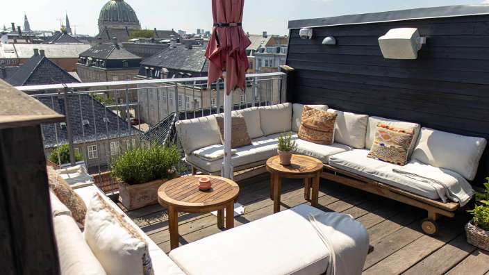 Ein Wohnzimmer auf einem Dach mit einem roten Regenschirm