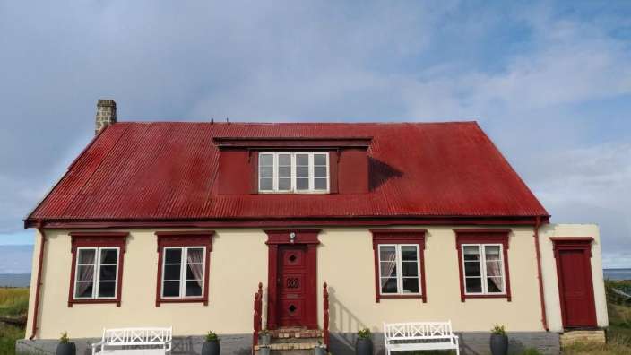 Ein weißes Haus mit einem roten Dach und weißen Fenstern