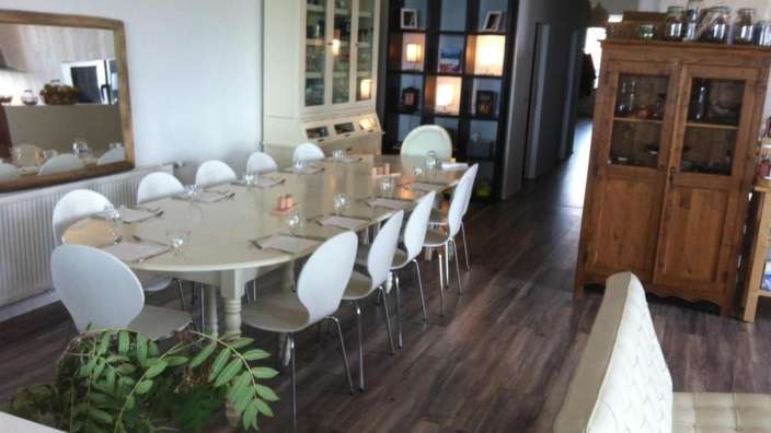 Ein Esszimmer mit einem langen Tisch und weißen Stühlen