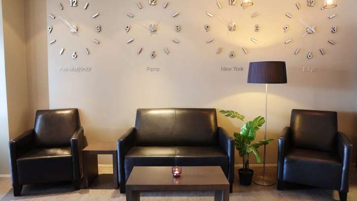 Ein Wohnzimmer mit Couch und Stühlen und Uhren an der Wand