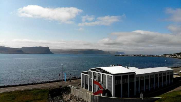 Ein großes weißes Gebäude steht in der Nähe eines großen Gewässers