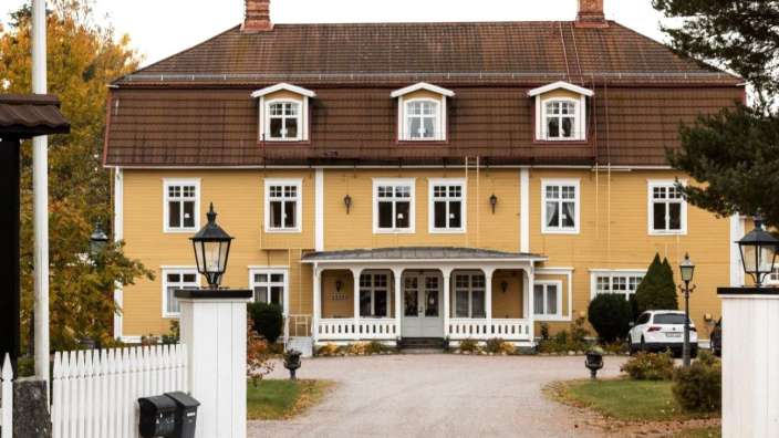 Ein großes gelbes Haus mit einem weißen Zaun davor