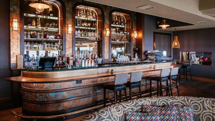 Eine lange Bar in einem Restaurant mit vielen Gläsern und Stühlen