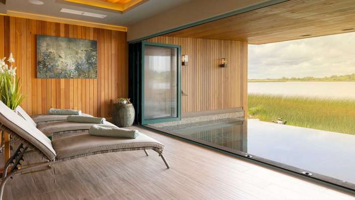 Ein Zimmer mit Liegestühlen und einem großen Fenster mit Blick auf einen See