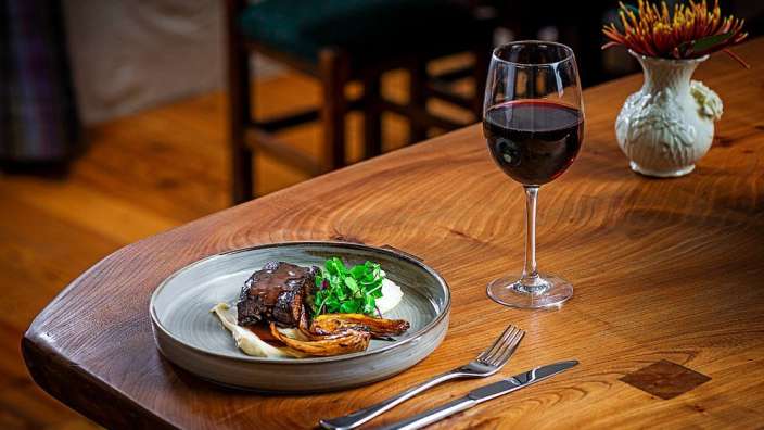 Ein Teller mit Essen und ein Glas Wein auf einem Holztisch