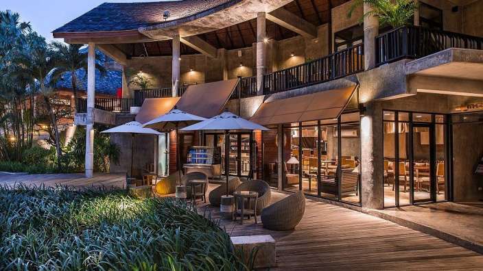 Ein großes Gebäude mit vielen Möbeln und Sonnenschirmen