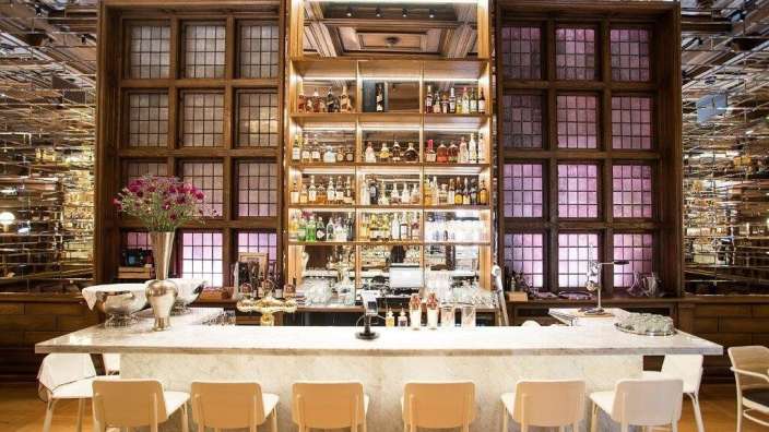 Eine Bar mit weißen Stühlen und vielen Flaschen Alkohol