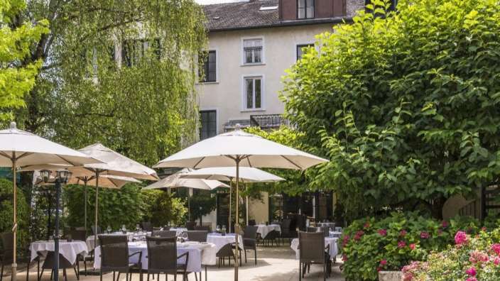 Eine Terrasse mit Tischen und Stühlen und Regenschirmen vor einem Gebäude
