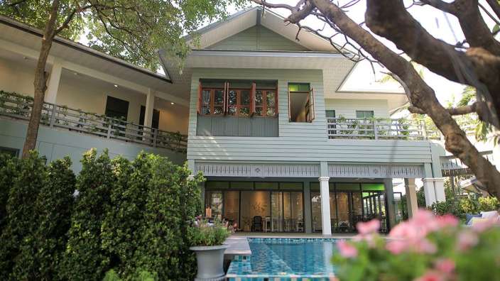 Ein grünes Haus mit einem Pool davor