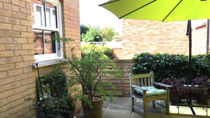 Ein grüner Regenschirm steht auf einer Terrasse vor einem Backsteingebäude
