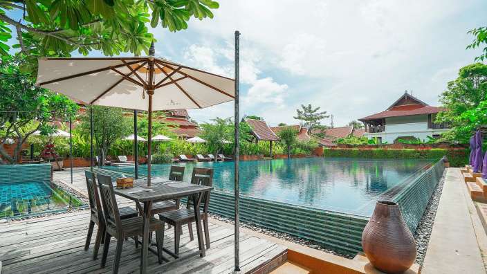 Ein schwimmbad mit einem tisch und stühlen davor