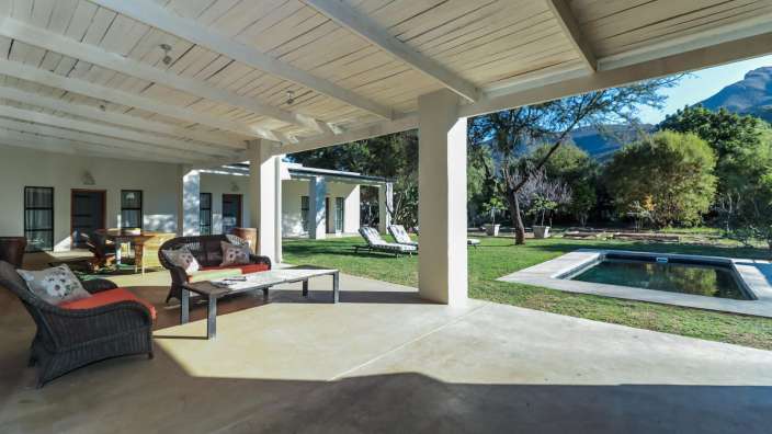 Ein Wohnzimmer mit einem Couchtisch und Stühlen neben einem Swimmingpool