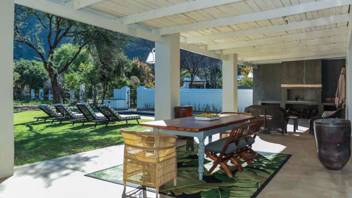 Eine Terrasse mit Tisch und Stühlen und einem Teppich mit Palmblättern darauf