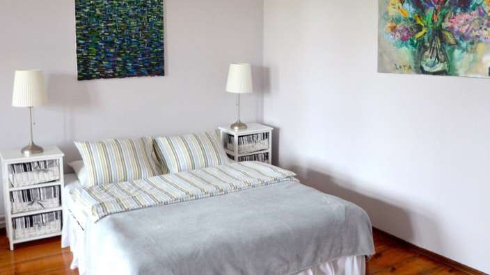 Ein Schlafzimmer mit einem Bett und zwei Nachttischen und einem Gemälde an der Wand