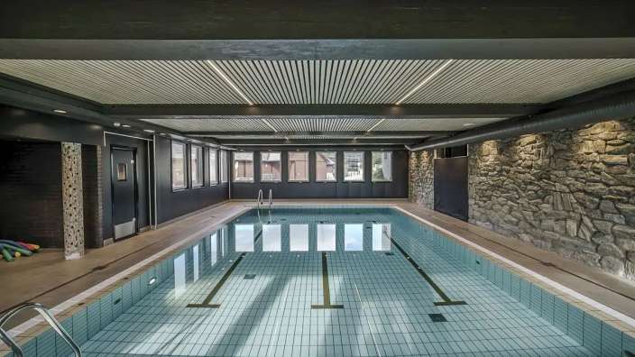 Ein Hallenbad mit Steinwänden und vielen Fenstern