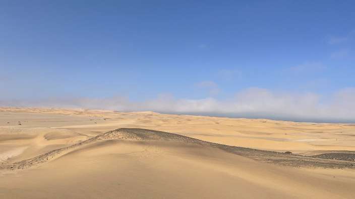 Eine Wüste mit großen Sanddünen und einem blauen Himmel