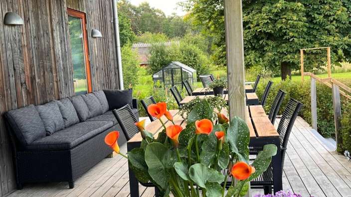 Eine Couch sitzt auf einem Deck neben einem Tisch und Stühlen