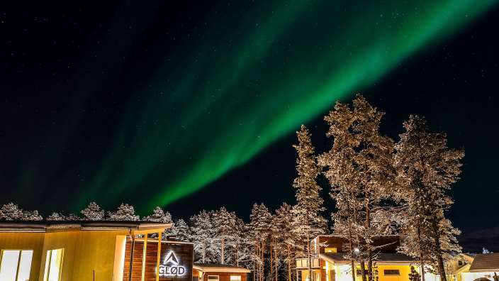 Das nordlicht scheint über einem gebäude mit a glod darauf