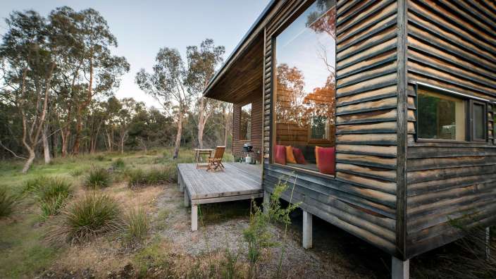Ein Holzhaus mit einem großen Fenster und einem Holzdeck
