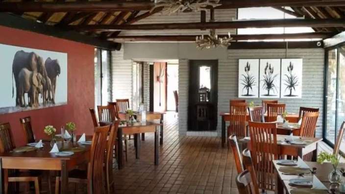 Ein Esszimmer mit Tischen und Stühlen und einem Gemälde von Elefanten an der Wand .