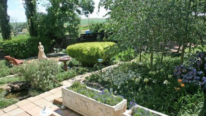 Ein Garten mit vielen Blumen und einer Statue