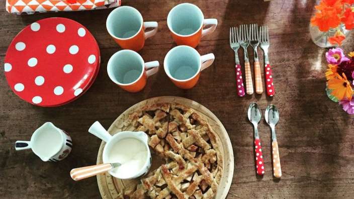 Auf einem tisch steht ein apfelkuchen mit milch und löffeln
