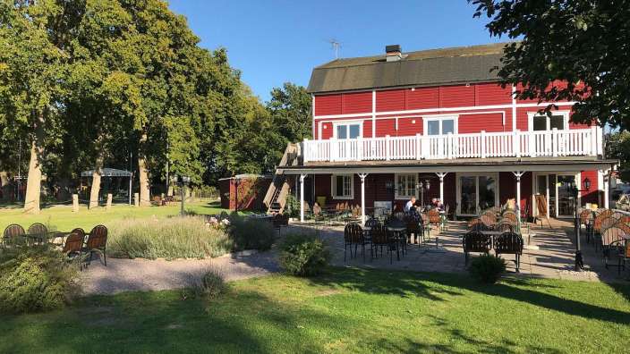 Eine rote Scheune mit einem weißen Deck und Tisch und Stühlen davor