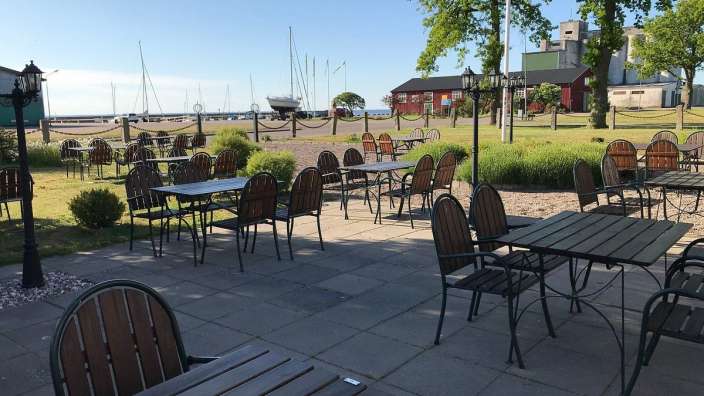 Tische und Stühle auf einer Terrasse mit einem Boot im Hintergrund