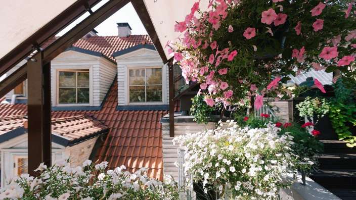 Ein Balkon mit rosa und weißen Blumen und einem Dach im Hintergrund