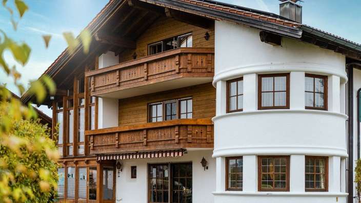 Ein weißes Haus mit einem Holzbalkon und vielen Fenstern