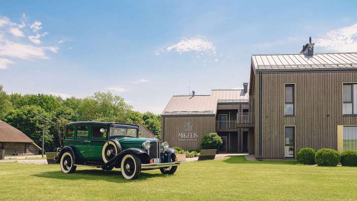 Ein grünes Auto steht vor einem Gebäude mit der Aufschrift mikelis