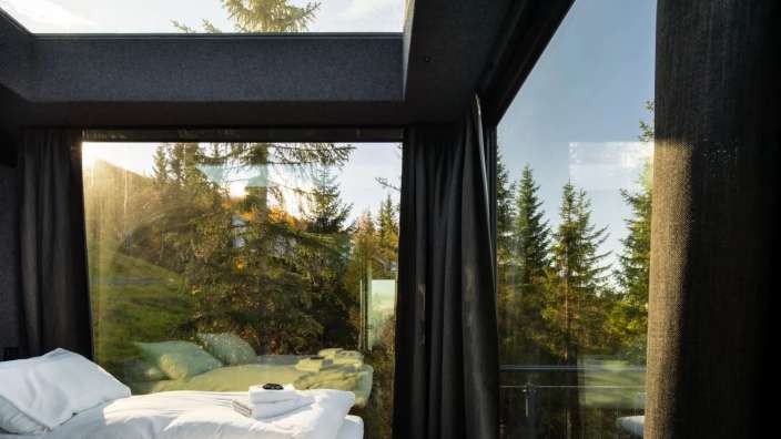 Ein Schlafzimmer mit einem Bett und einem Fenster mit Blick auf einen Wald