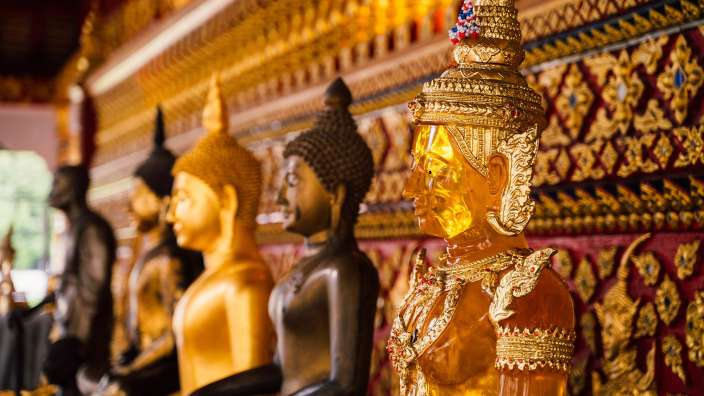 Eine Reihe von goldenen buddhistischen Statuen in einem Tempel