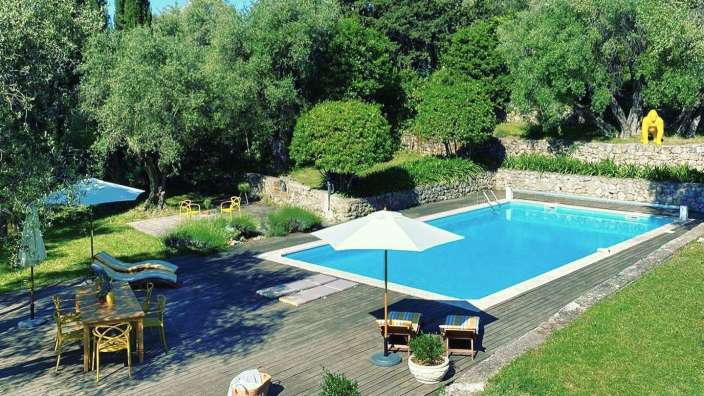 Ein großer Swimmingpool umgeben von Bäumen und einem Holzdeck