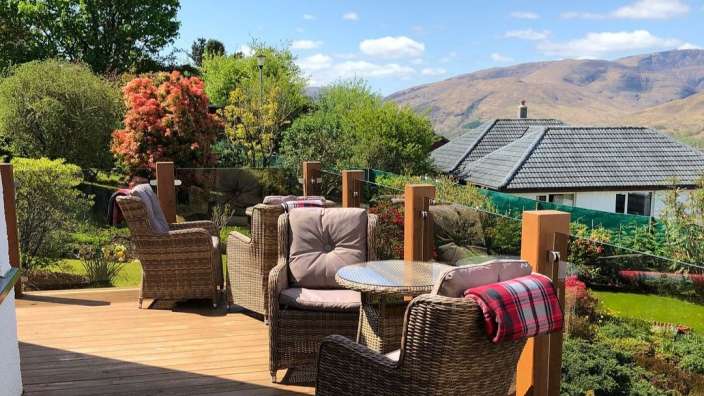 Ein Deck mit Stühlen und einem Tisch und einem Haus im Hintergrund