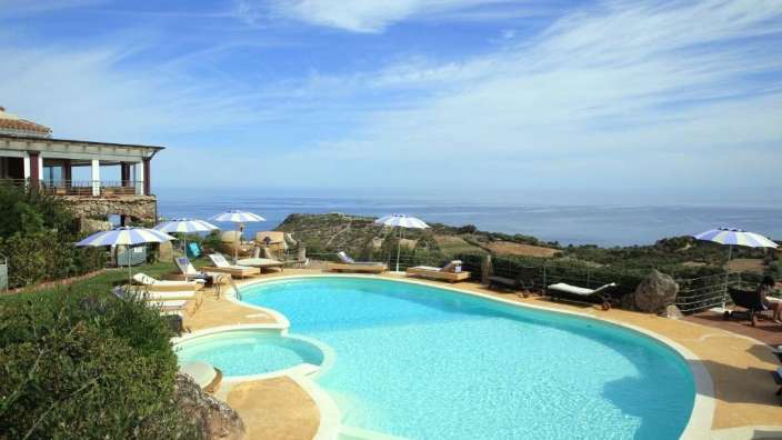 Ein großer Pool mit Liegestühlen und Sonnenschirmen umgeben