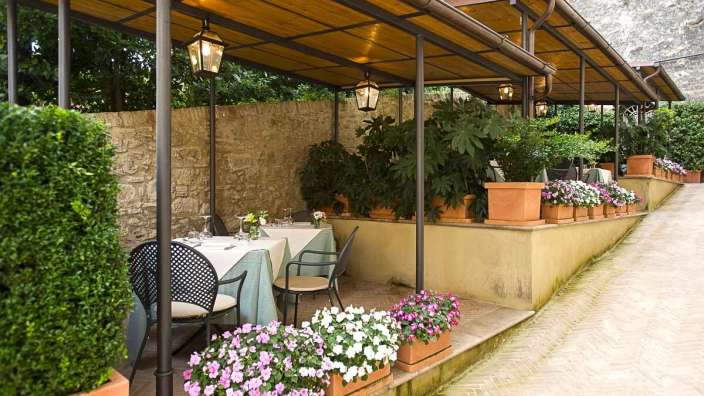 Ein Tisch und Stühle unter einer überdachten Terrasse mit Blumentöpfen