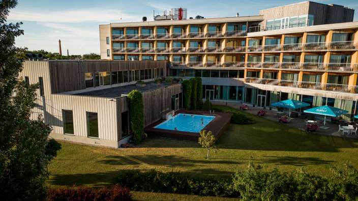 Ein großes Hotel mit einem Pool und blauen Sonnenschirmen