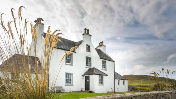 Ein großes weißes Haus mit einer Steinmauer davor