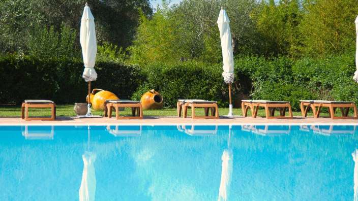 Ein Swimmingpool mit Liegestühlen und Sonnenschirmen umgeben