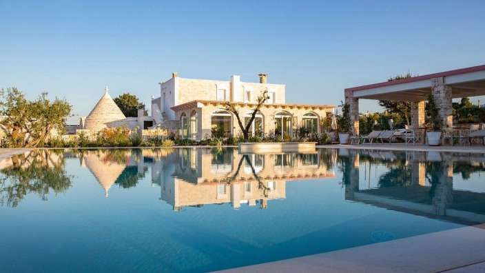 Ein großer Swimmingpool mit einem weißen Haus im Hintergrund