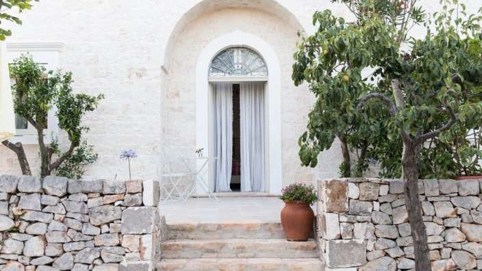 Ein weißes Gebäude mit einer Steinmauer davor