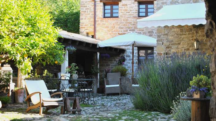 Eine Terrasse mit Tisch und Stühlen und einem weißen Regenschirm