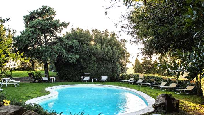 Ein großer Swimmingpool umgeben von Liegestühlen und Bäumen