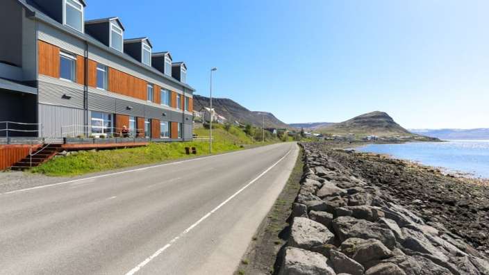 Eine Straße mit einem Gebäude an der Seite und einem Berg im Hintergrund