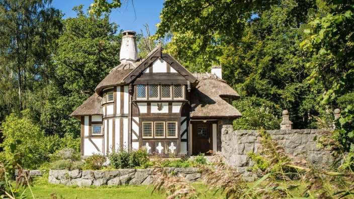 Ein Schwarz-Weiß-Haus mit Strohdach und Steinmauer