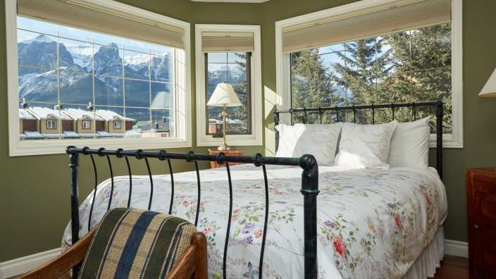 Ein Schlafzimmer mit einem Bett und zwei Fenstern mit Blick auf die Berge