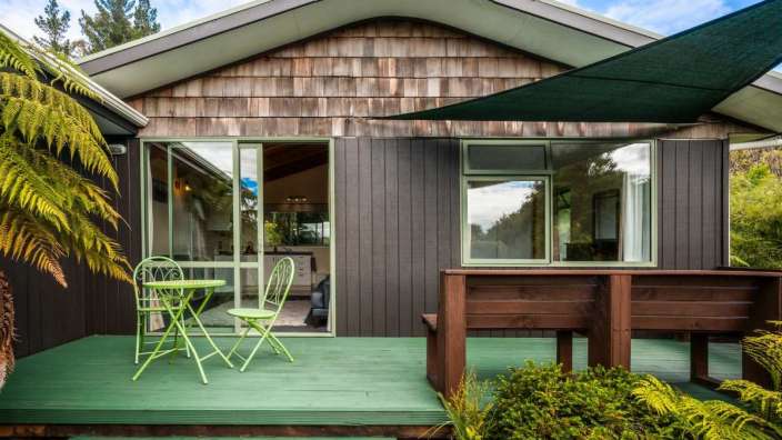 Eine grüne Terrasse mit einem Tisch und Stühlen vor einem Haus
